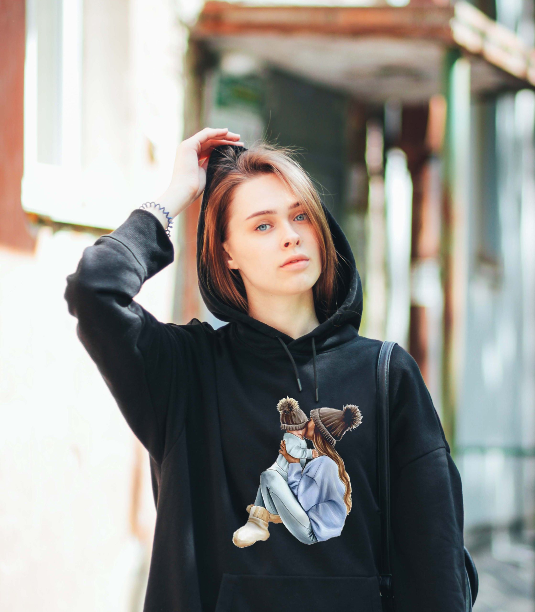 Candid portrait of young beautiful long hair girl fashion model hipster in black hoody on the city street