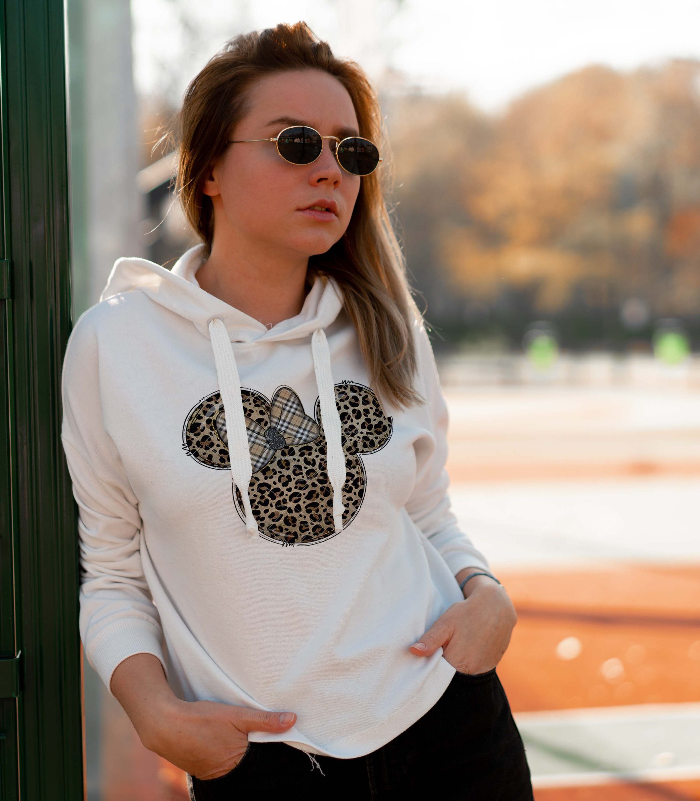 Outdoor close up portrait of young beautiful woman with long hair in sunglasses, dressed in a white hoodie sweater, near the sportsground. youth culture summer pastime